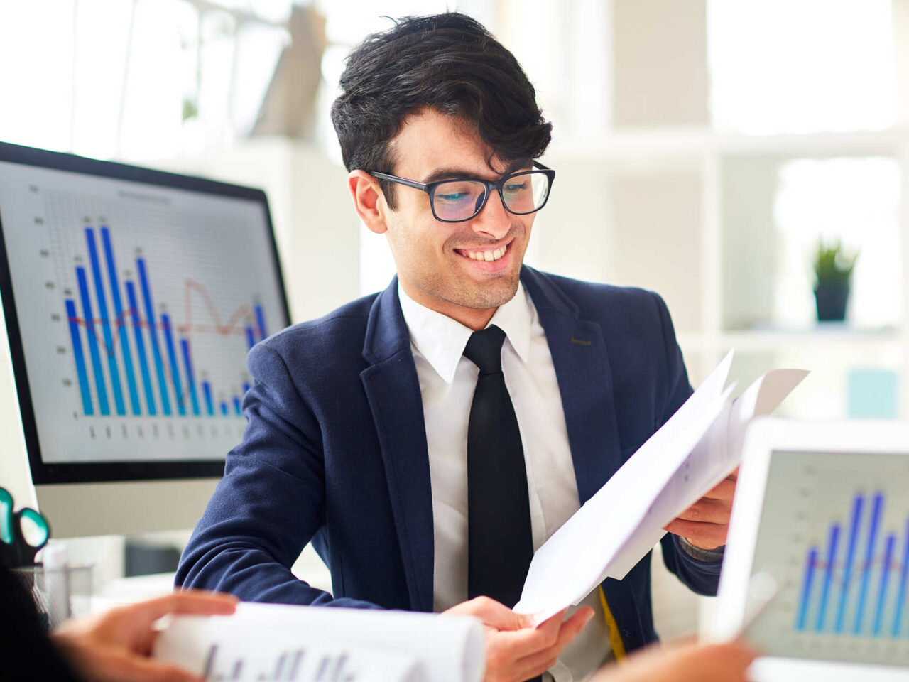 Young financier reading documents and discussing financial data with colleague